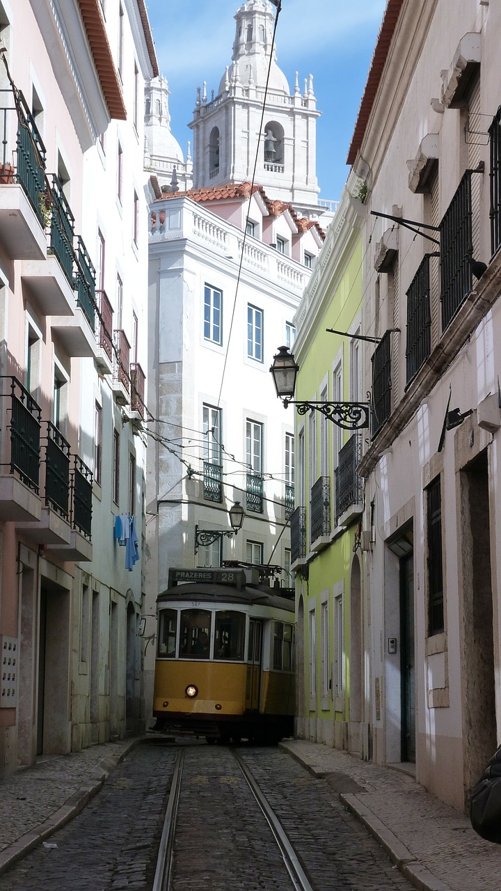 Tram giallo attraversa una stretta strada del centro di Lisbona